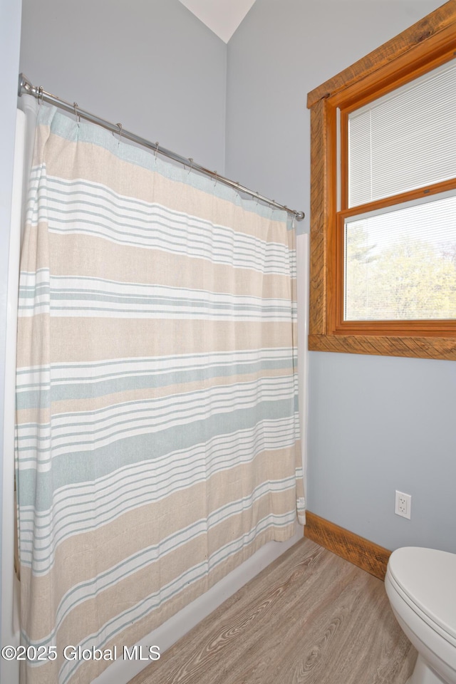 bathroom featuring baseboards, wood finished floors, toilet, and a shower with curtain