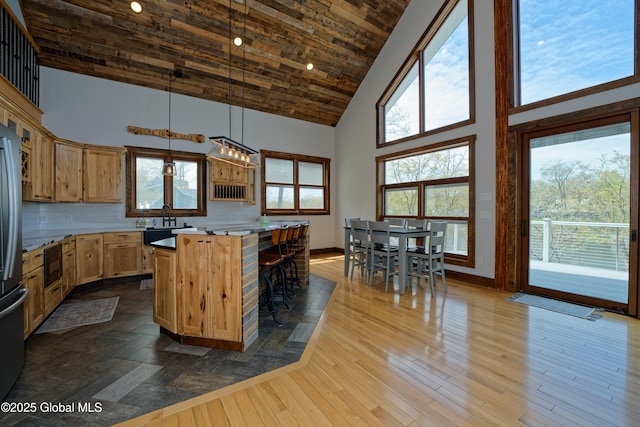kitchen with pendant lighting, high vaulted ceiling, baseboards, and a kitchen island