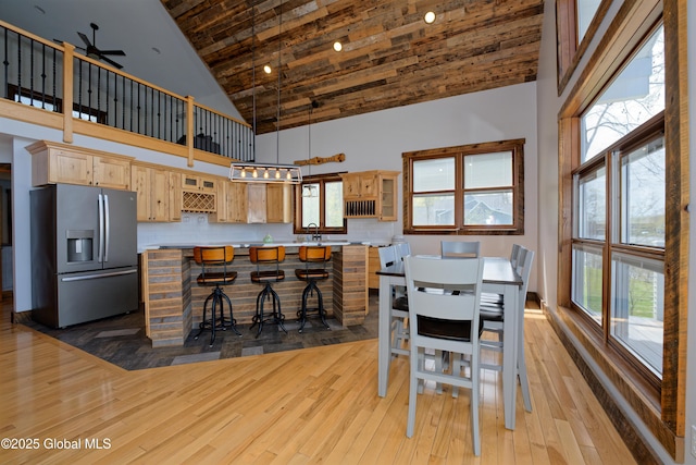 dining space with ceiling fan, a wealth of natural light, high vaulted ceiling, and light wood-type flooring