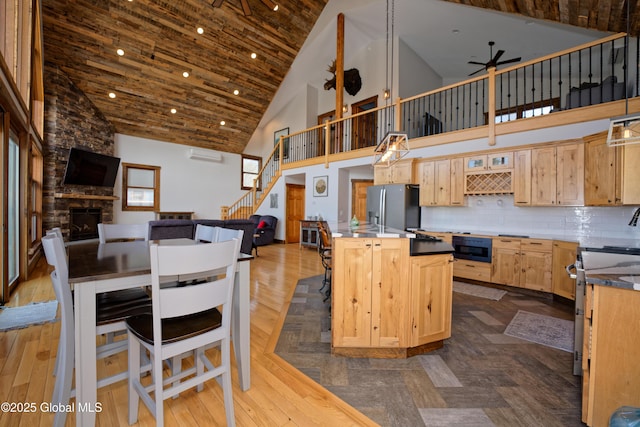 kitchen with light brown cabinetry, stainless steel refrigerator with ice dispenser, open floor plan, and a ceiling fan