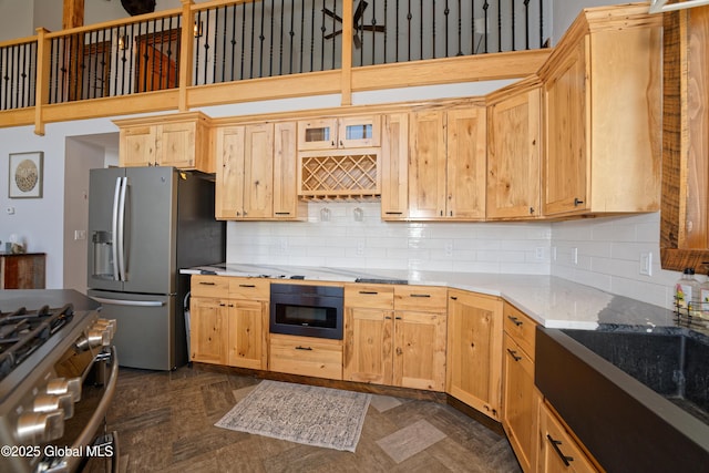 kitchen with a towering ceiling, light brown cabinetry, tasteful backsplash, light stone countertops, and stainless steel appliances