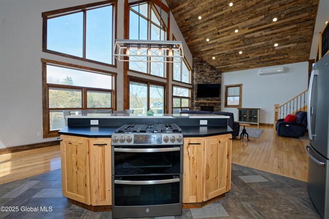kitchen featuring light brown cabinetry, appliances with stainless steel finishes, baseboards, and high vaulted ceiling