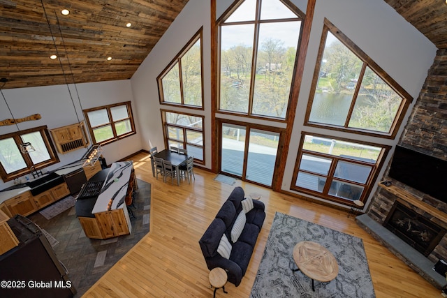 living room featuring wood ceiling, a fireplace, wood finished floors, high vaulted ceiling, and recessed lighting