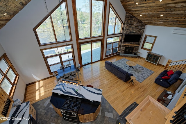 living area featuring a fireplace, high vaulted ceiling, wood finished floors, and a wall mounted air conditioner