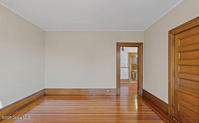 empty room with baseboards, ornamental molding, and wood finished floors