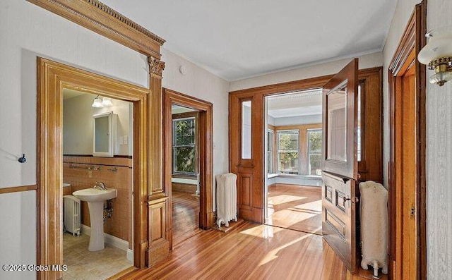 hall featuring light wood-style floors, radiator, and ornamental molding