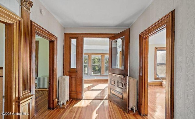 hall with baseboards, radiator, and wood finished floors