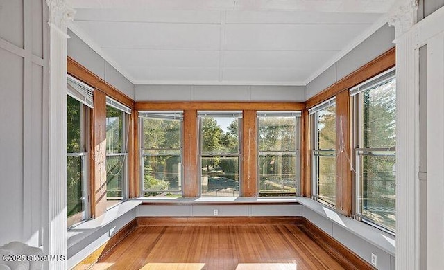 unfurnished sunroom with baseboards, ornamental molding, and wood finished floors
