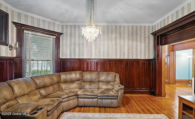 living room with crown molding, a chandelier, wainscoting, and wood finished floors