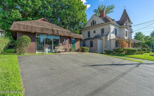 view of front of home with a chimney and aphalt driveway