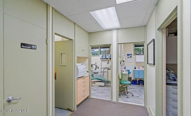 hallway with carpet and a paneled ceiling