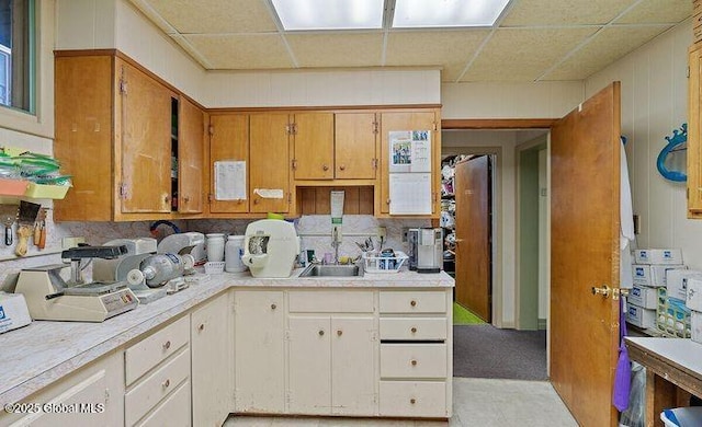 kitchen with brown cabinetry, light countertops, and a sink