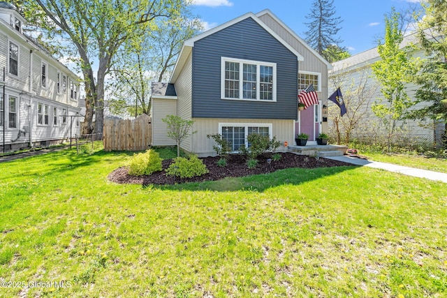 tri-level home featuring a front lawn, board and batten siding, and fence