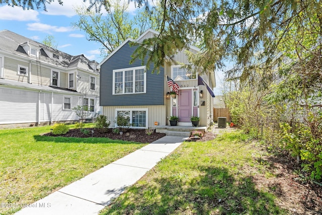 view of front of home with board and batten siding, cooling unit, and a front lawn