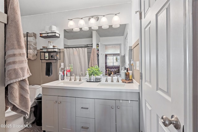 full bath with double vanity, a sink, curtained shower, and toilet