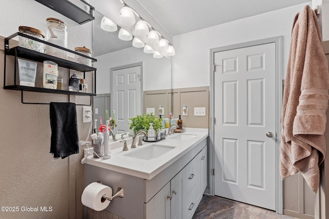 bathroom with double vanity, a sink, marble finish floor, and a textured wall