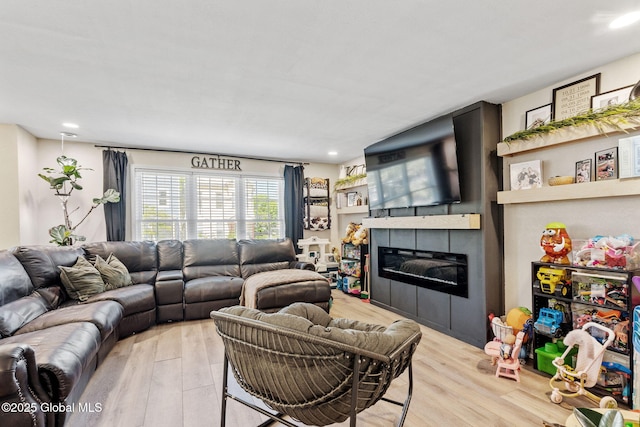 living area featuring recessed lighting, a glass covered fireplace, and light wood finished floors