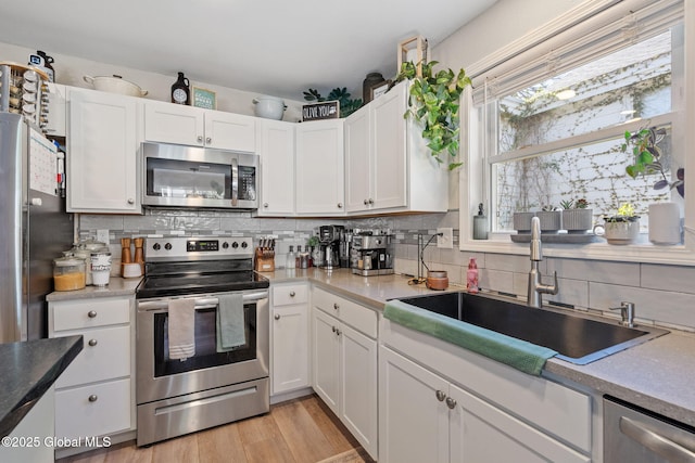 kitchen featuring a sink, white cabinets, backsplash, and stainless steel appliances