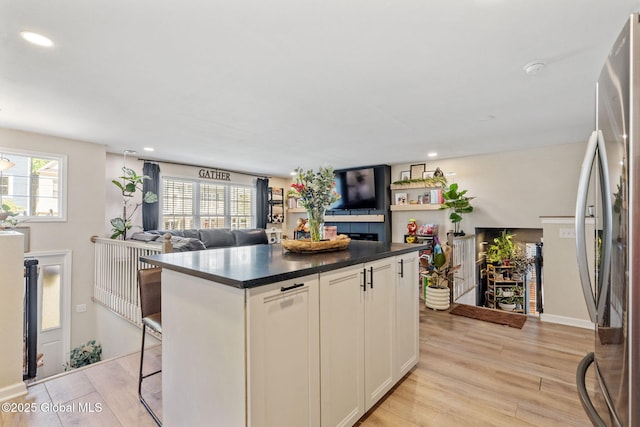 kitchen with freestanding refrigerator, light wood finished floors, open floor plan, and dark countertops