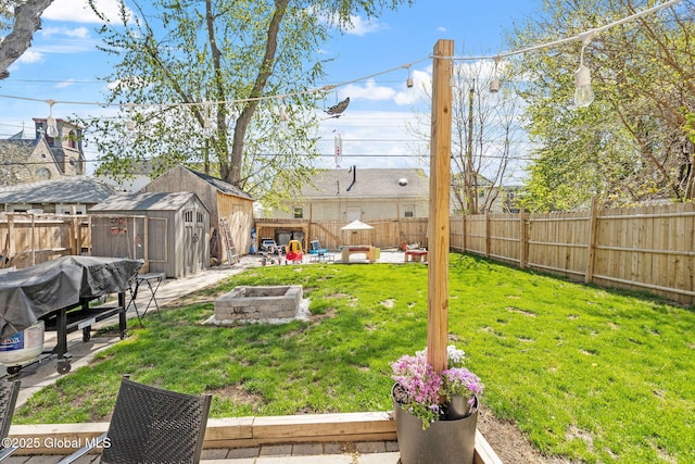 view of yard with an outdoor structure, a shed, a fenced backyard, a patio, and a fire pit