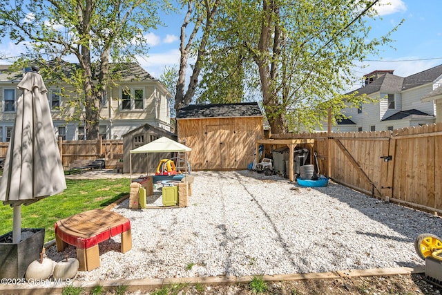 view of yard with a storage shed, a patio, an outdoor structure, and a fenced backyard