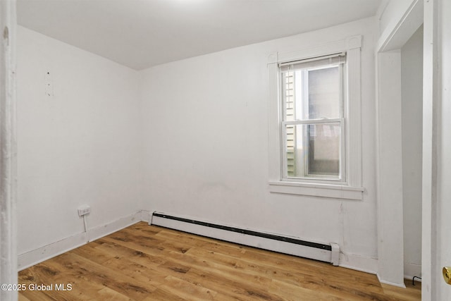spare room featuring a baseboard heating unit and light wood-type flooring