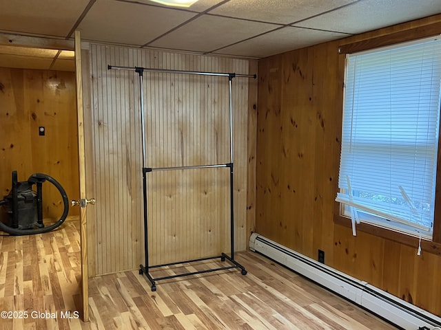 interior space featuring wood walls, a baseboard heating unit, and light wood-style floors