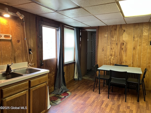 dining area featuring a paneled ceiling, wood finished floors, and wooden walls