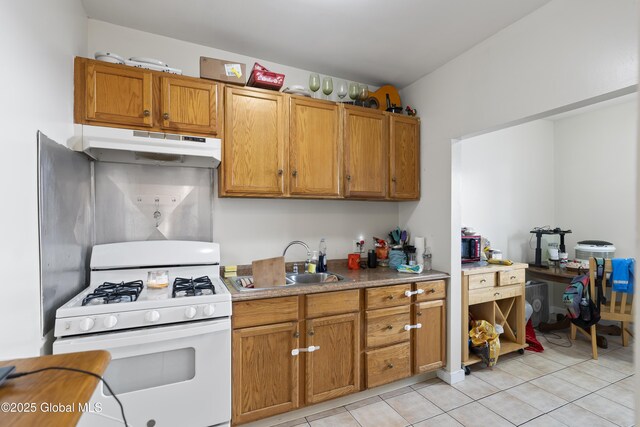 100 3rd St, Waterford, NY 12188 - kitchen with brown cabinets, a sink, light tile patterned floors, under cabinet range hood, and white range with gas stovetop