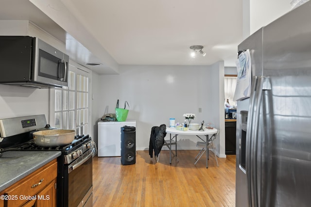 100 3rd St, Waterford, NY 12188 - kitchen featuring dark countertops, baseboards, brown cabinets, light wood-style flooring, and appliances with stainless steel finishes
