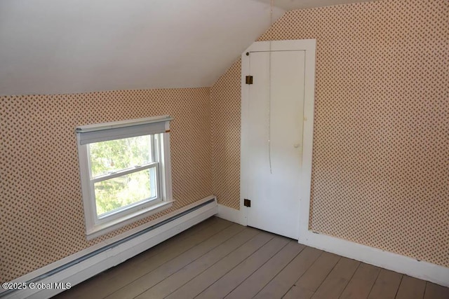 bonus room featuring wood finished floors, baseboards, baseboard heating, wallpapered walls, and vaulted ceiling
