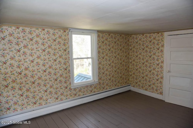 spare room featuring a baseboard heating unit, wallpapered walls, and wood finished floors