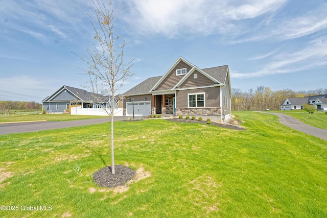 craftsman inspired home with stone siding, an attached garage, a front lawn, and aphalt driveway