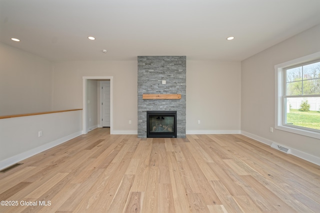unfurnished living room with recessed lighting, visible vents, a stone fireplace, and light wood-style floors