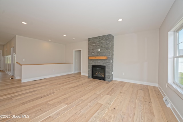 unfurnished living room featuring light wood-style floors, baseboards, recessed lighting, and a stone fireplace