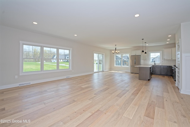 unfurnished living room featuring an inviting chandelier, light wood-style floors, and recessed lighting