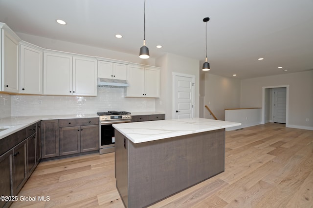 kitchen featuring backsplash, under cabinet range hood, stainless steel range with gas cooktop, and light wood-style flooring