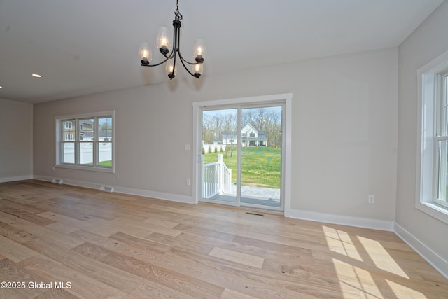 interior space featuring light wood-style floors, baseboards, plenty of natural light, and a notable chandelier