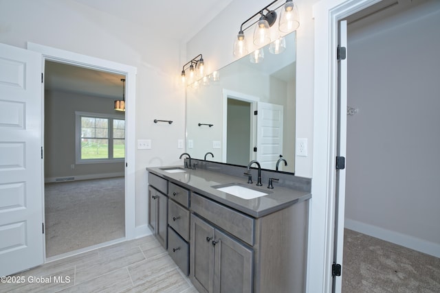 full bath with double vanity, baseboards, visible vents, and a sink