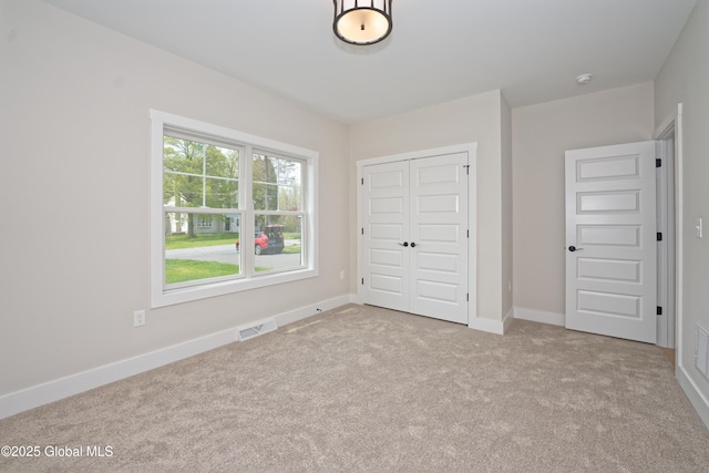 unfurnished bedroom featuring carpet floors, baseboards, visible vents, and a closet