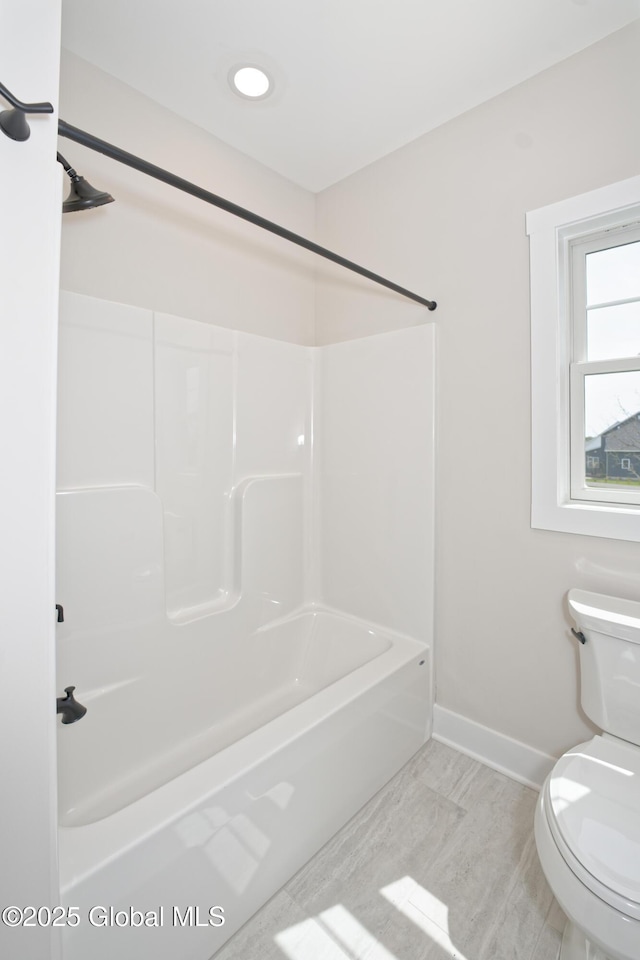 bathroom featuring shower / bath combination, baseboards, and toilet