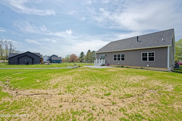 back of property with a lawn and roof with shingles