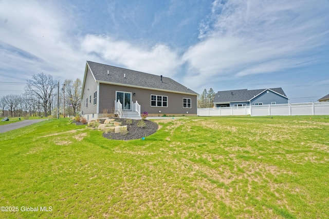 rear view of house with a lawn, fence, and entry steps