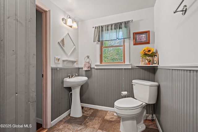 3550 Boyhaven Rd, Middle Grove, NY 12850 - bathroom featuring toilet, baseboards, stone finish flooring, and wainscoting