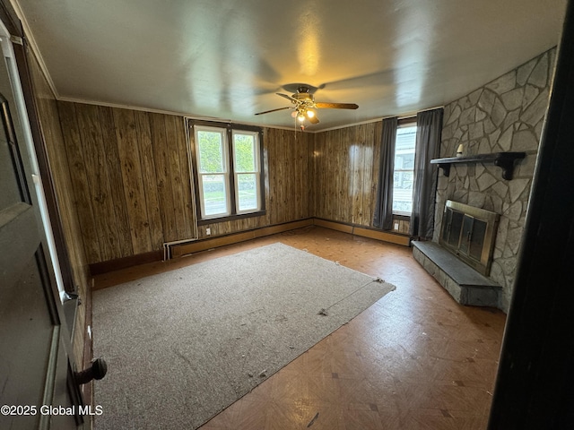 6 Cline St, Dolgeville, NY 13329 - unfurnished living room featuring healthy amount of natural light, ceiling fan, wooden walls, and a fireplace