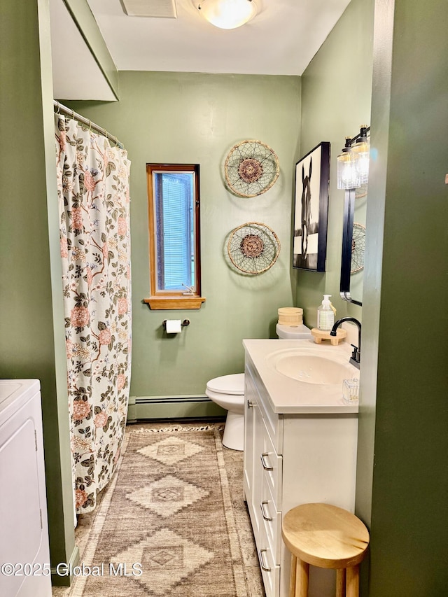 full bath featuring a shower with curtain, washer / clothes dryer, vanity, a baseboard heating unit, and toilet