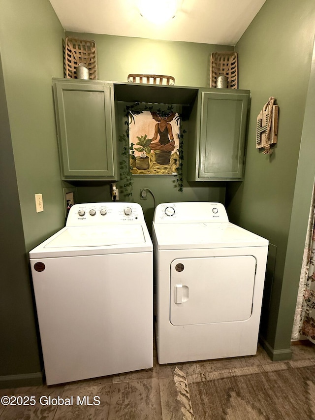 washroom featuring cabinet space, baseboards, and washer and clothes dryer