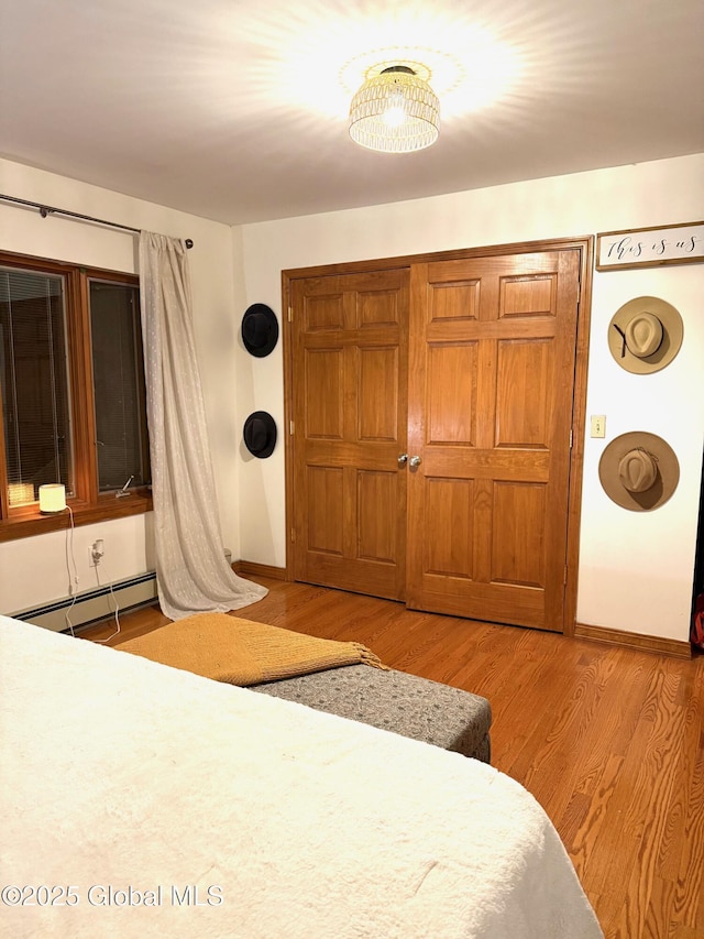 bedroom with baseboards, a baseboard radiator, and wood finished floors