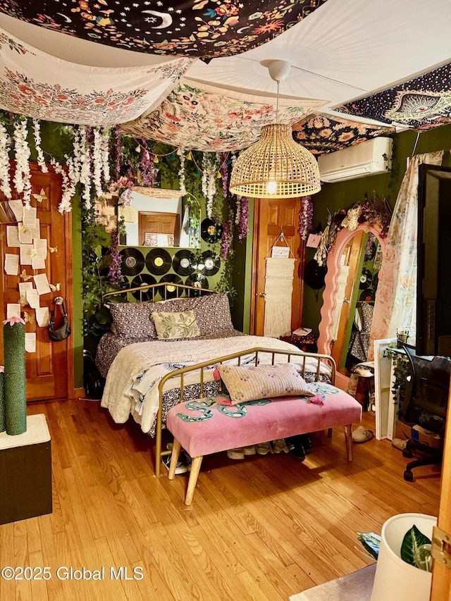 bedroom with a wall mounted air conditioner and wood finished floors