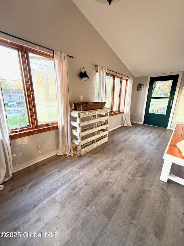 unfurnished living room featuring baseboards, lofted ceiling, and wood finished floors